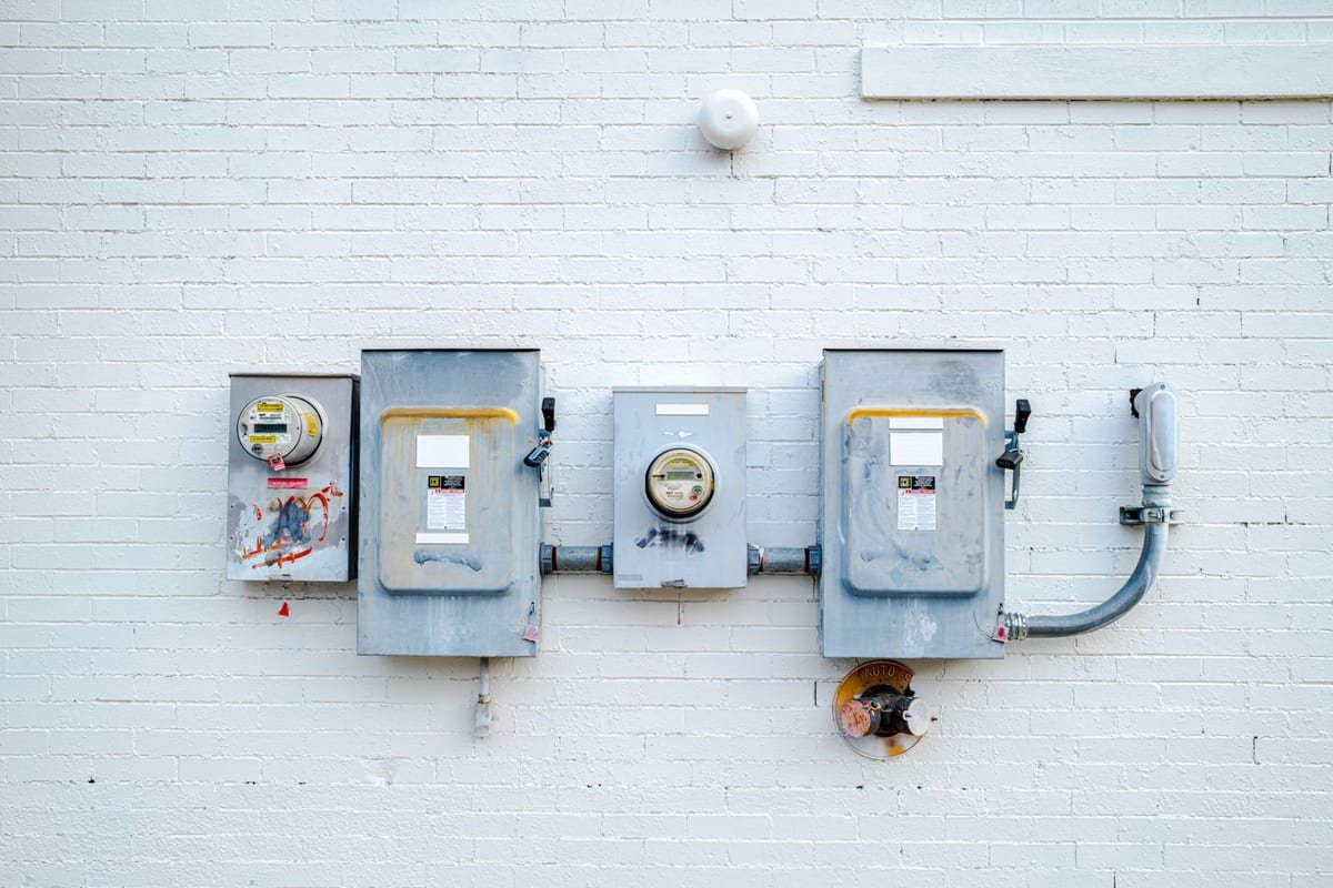Medidores de energia elétrica instalados na parede branca de um prédio residencial