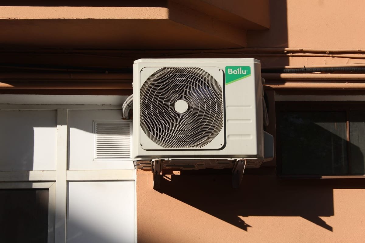 Unidade externa de ar-condicionado instalada na fachada de um prédio, exposta ao sol