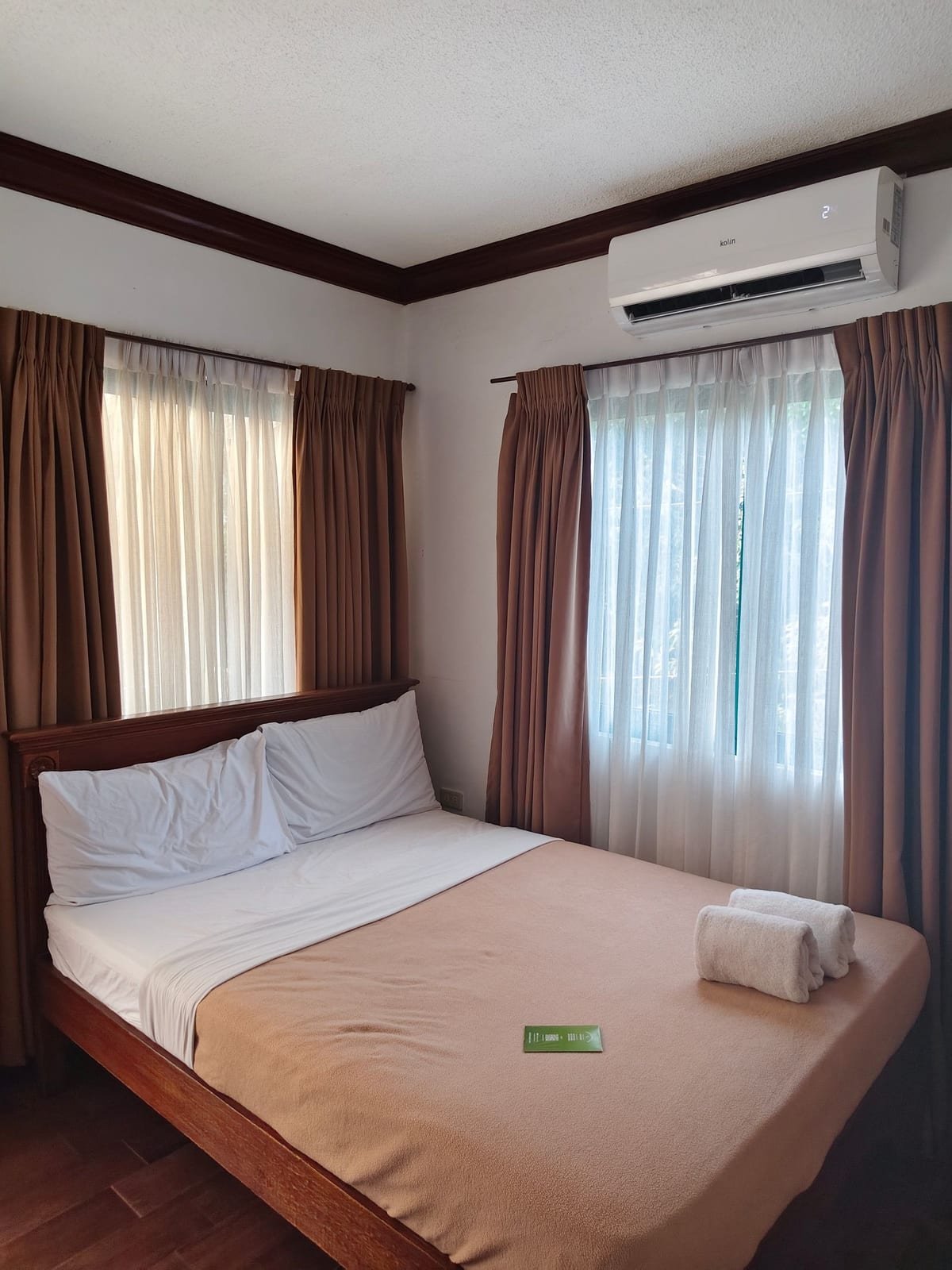 Quarto de hospedagem com cama, cortina e a unidade interna do ar-condicionado na parede
