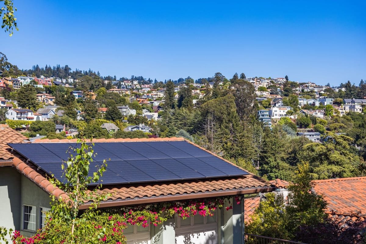 Casa com módulos fotovoltaicos instalados sobre o telhado de telha cerâmica, em bairro residencial