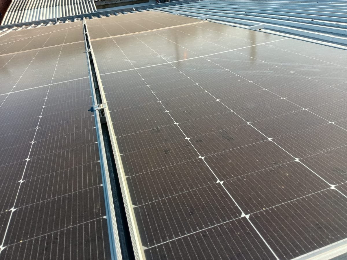 Módulos fotovoltaicos cobertos por uma camada uniforme de sujeira, vistos de perto no telhado